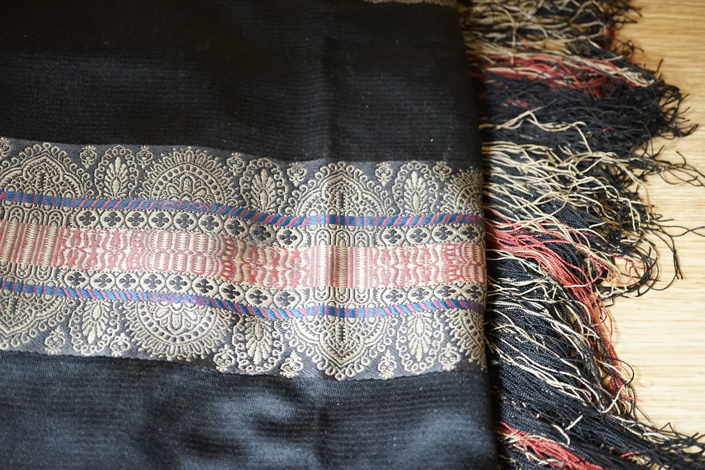 A Victorian black silk shawl woven, woven with multi-coloured Paisley designed stripes bordered with a silk multi-coloured fringe, 184cms square (not including fringe)